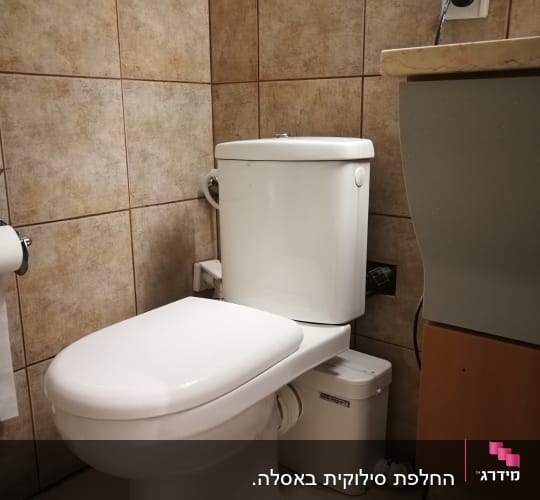 אסלה עם חיבורי צנרת בחדר אמבטיה